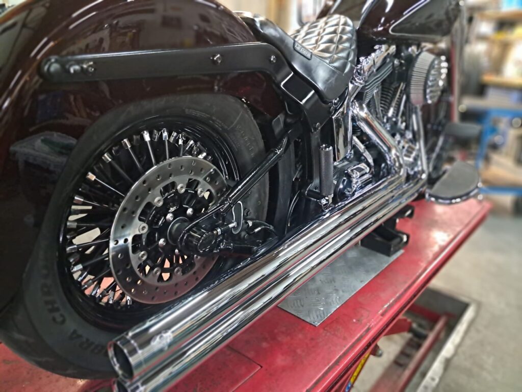Achterwiel, remschijf en chromen uitlaten van een Harley-Davidson
